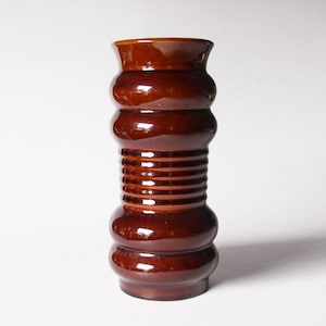 Może przedstawiać: Brązowy ceramiczny wazon z fakturowanym, żebrowanym wzorem. Wazon ma szeroki otwór i wąską podstawę.