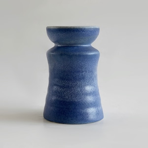 May include: A blue ceramic vase with a textured, slightly iridescent glaze. The vase has a wide mouth and a narrow base.