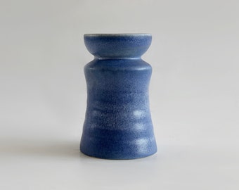 Könnte beinhalten: Eine blaue Keramikvase mit einer strukturierten, leicht schillernden Glasur. Die Vase hat eine breite Öffnung und einen schmalen Boden.