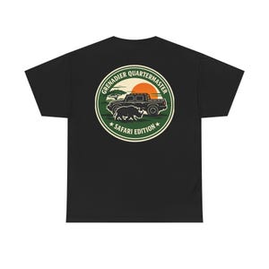 May include: Black t-shirt with a circular graphic reading "Grenadier Quartermaster Safari Edition." The design features a truck, rhino, and sunset in green, orange, and white. The shirt is made of a soft, comfortable material.