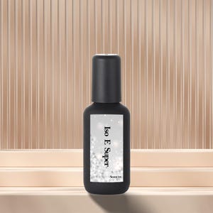 Puede incluir: Una botella negra con tapa negra. La etiqueta dice "Iso E Super" con "Scent 01" debajo. El fondo es de color beige claro con líneas verticales.