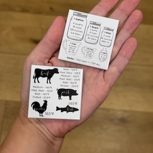 May include: Two white square magnets with cooking conversion charts and meat temperatures. One magnet shows liquid measurements in gallons, quarts, pints, and cups. The other magnet displays beef, pork, poultry, and fish temperatures in Fahrenheit.