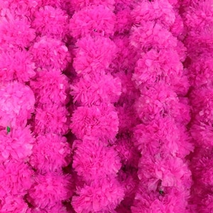 May include: Close-up of a vibrant display of bright pink, fluffy artificial flowers. The flowers are densely packed together, creating a textured, eye-catching background. The image showcases a floral arrangement, perfect for decorative purposes.
