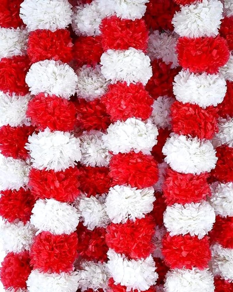 May include: A close-up of a decorative garland composed of alternating rows of red and white pom-poms. The pom-poms are densely packed, creating a textured and vibrant display. The garland is suitable for festive occasions.