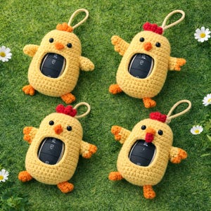 May include: Four yellow crochet chicken key fob holders with orange accents, red combs, and black eyes are arranged on green grass. Each holder has a loop for attaching to a keychain and a cutout to display a car key.