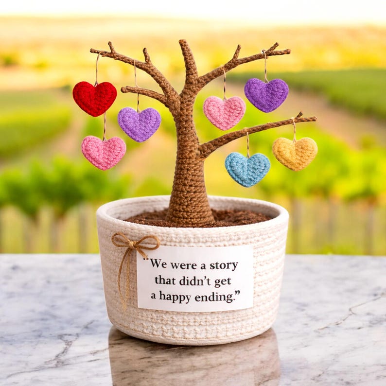 May include: A handcrafted crochet tree with a brown trunk and branches, planted in a white woven pot. The tree is adorned with hanging crochet hearts in red, pink, purple, blue, and yellow. A tag reads, "We were a story that didn't get a happy ending."