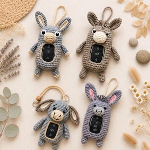 May include: Four handmade crochet key fob covers shaped like donkeys and rabbits. The covers are in shades of grey and brown, with details such as ears, eyes, and key fob buttons. Each has a loop for attaching to a keyring.