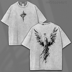 May include: Two gray t-shirts with black graphic designs. One shirt features an eye and sword design, the other a winged figure. The shirts have a stone-washed appearance and a crew neck.