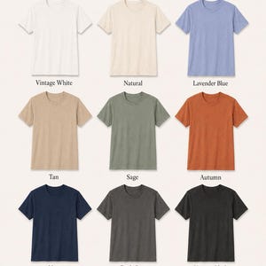 May include: A color chart displaying nine short-sleeved crew neck t-shirts in various colors labeled Vintage White, Natural, Lavender Blue, Tan, Sage, Autumn, Navy, Dark Grey, and Vintage Black. The text Available Colors appears at the top.