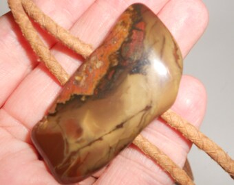 May include: A brown, tan, and red agate stone pendant on a brown leather cord. The stone has a unique, swirling pattern.