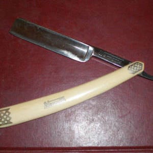 May include: A vintage straight razor with a white bone handle and a silver blade. The blade has the word "Wernicke" engraved on it.