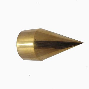 Op de afbeelding: Een massief messing object met een conische vorm, met een brede, cilindrische basis die taps toeloopt naar een scherpe punt. Het oppervlak is gepolijst en reflecterend, met een gouden uitstraling. Het object staat tegen een effen witte achtergrond.