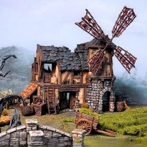 May include: A miniature model of a weathered windmill building with a stone base, timber-framed walls, and a dark shingled roof. The structure features a large rotating blade assembly with tattered red fabric, wooden crates, barrels, and a cart.
