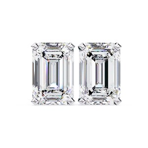 May include: A pair of sparkling emerald-cut diamond stud earrings. Each earring showcases a rectangular, clear gemstone with multiple facets, set in a white metal. The earrings are presented against a plain white backdrop, emphasising their sparkle.
