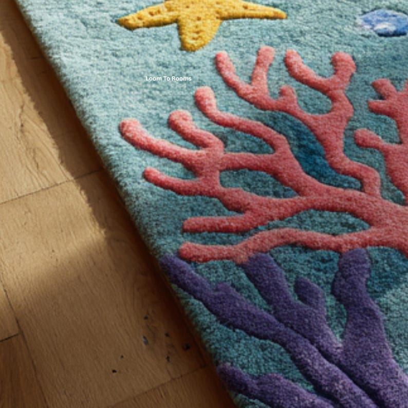 Puede incluir: Primer plano de una alfombra turquesa con un dise&ntilde;o de arrecife de coral. La alfombra presenta una estrella de mar amarilla, coral rosa y morado y un pez azul. El texto "Loom To Rooms" es visible en la alfombra.