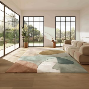 Könnte beinhalten: Ein großer, farbenfroher Teppich mit einem abstrakten geometrischen Design. Der Teppich hat eine Palette gedämpfter Farben, darunter Braun, Grün und Beige. Der Teppich befindet sich in einem modernen Wohnzimmer mit großen Fenstern und einem beigen Sofa.