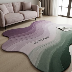 May include: An abstract area rug with a wavy design, featuring a gradient of colours from purple to green. The rug is made of a soft material and is placed on a wooden floor. The rug's design creates a layered effect. The text "Loomtoroom" is visible.
