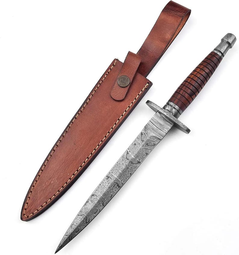 May include: A double-edged dagger featuring a patterned Damascus steel blade, a dark wood handle with horizontal grooves, and a metal crossguard. The knife is accompanied by a brown leather sheath with visible stitching and a metal snap button closure.