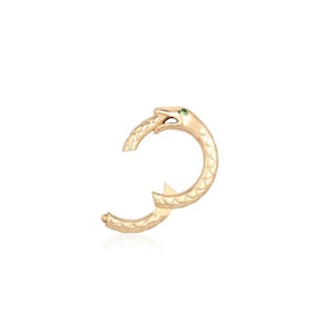 May include: A gold hoop earring shaped like a coiled snake with a textured, scale-like pattern along its body. The snake head features a single small green gemstone set as an eye. The earring has a hinged mechanism for closure and a polished finish.