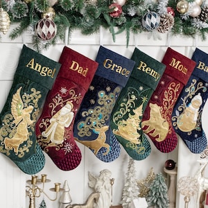 May include: Six personalised Christmas stockings hanging in a row, featuring embroidered names including Angel, Dad, Grace, Remy, Mom, and Banks. Each stocking displays unique gold-toned holiday motifs like an angel, Santa, reindeer, tree, bear, and snowman.