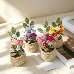 Peut inclure: Quatre petites plantes en pot réalisées en fil crocheté. Chaque plante présente des feuilles vertes et des fleurs colorées dans des tons de rose, violet, jaune et orange, agrémentées de petites perles blanches. Les pots sont beiges et texturés.
