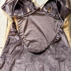 May include: A dark gray velvet camisole featuring delicate beige lace trim along the neckline and sides. The garment includes thin adjustable shoulder straps and a central panel with a smooth fabric finish, showcasing a combination of soft textures.