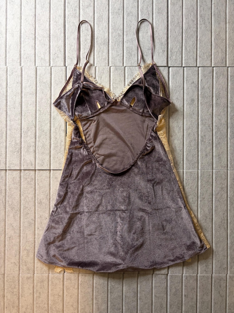 May include: A sleeveless chemise featuring a dark mauve velvet bodice with a deep scoop back and thin adjustable shoulder straps. The garment is accented with cream-colored lace trim along the neckline and side panels, creating a layered look.