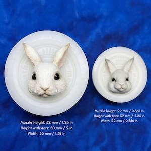 Op de afbeelding: Twee ronde siliconen mallen met koningengezichten. De grotere mal heeft een snuithoogte van 32 mm, een hoogte met oren van 50 mm en een breedte van 35 mm. De kleinere mal heeft een snuithoogte van 22 mm, een hoogte met oren van 32 mm en een breedte van 22 mm.