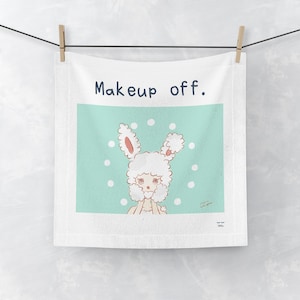May include: A white square towel featuring the text "Makeup off." in dark blue letters. The center graphic shows a cartoon character with fluffy white hair and rabbit ears against a light mint green background with white polka dots.