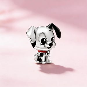Può includere: Un charm argentato raffigurante un cucciolo di dalmata dei cartoni animati. Il cucciolo ha macchie nere, orecchie nere e un collare rosso. Il charm è posto su uno sfondo rosa.