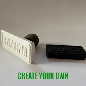 May include: A white rubber stamp with the word APPROVED in raised letters and a dark brown handle, positioned next to a black rectangular stamp with the word DENIED in raised letters. The text CREATE YOUR OWN appears in green at the bottom.
