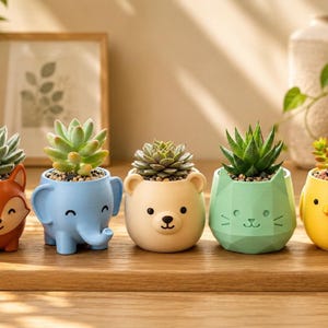 May include: A set of five small animal-shaped planters in orange, blue, beige, green, and yellow. Each planter features a unique character design, including a fox, elephant, bear, cat, and chick, and contains a small green succulent plant.
