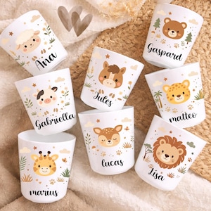 Pu&ograve; includere: Tazze in ceramica bianca con illustrazioni di animali, tra cui una pecora, una mucca, un cavallo, un orso, un ghepardo, un cervo, una giraffa e un leone. Ogni tazza ha un nome stampato: Ana, Gabriella, Jules, Gaspard, matteo, lucas, marius e Lisa.