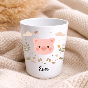 Pu&ograve; includere: Tazza in ceramica bianca con un'illustrazione di maiale rosa, nuvole, stelle e fiori. Il nome "Eva" &egrave; stampato in corsivo nero. La tazza ha un design stravagante.