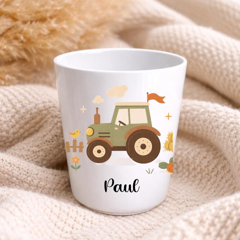 Puede incluir: Taza de cer&aacute;mica blanca con un dise&ntilde;o de tractor verde y marr&oacute;n, una peque&ntilde;a bandera naranja y el nombre "Paul". El dise&ntilde;o incluye un p&aacute;jaro amarillo, nubes y un peque&ntilde;o pajar.