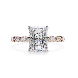 May include: An engagement ring with a large, rectangular-cut diamond. The central diamond is held by four prongs. The band is rose gold, embellished with smaller, marquise-cut diamonds set along the sides of the ring.