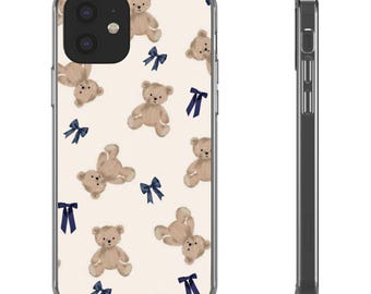 May include: A clear phone case featuring a repeating pattern of tan teddy bears and navy blue bows on a cream background. The case has a clear border and a black camera cutout.