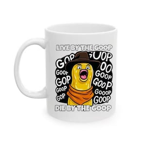 Può includere: Tazza in ceramica bianca con un personaggio dei cartoni animati con cappello da cowboy e sciarpa arancione, con il testo "LIVE BY THE GOOP" e "DIE BY THE GOOP". Il personaggio è giallo con la bocca aperta e la parola "GOOP".