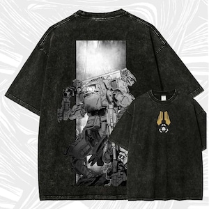 May include: Two black graphic t-shirts. The larger shirt displays a detailed robot illustration on the back. The smaller shirt has a gold and white emblem on the front. Both shirts have a vintage, washed look.
