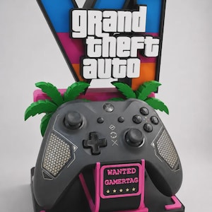 May include: A 3D display stand featuring the Grand Theft Auto VI logo in blue, pink, and orange, with green palm tree accents. A dark grey video game controller rests on the stand, which includes a pink sign labelled WANTED GAMERTAG with five stars.
