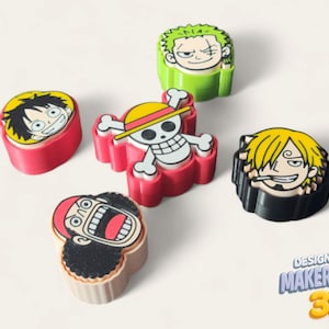 May include: A selection of colourful, 3D-printed character figures from the anime series One Piece. The figures depict characters such as Luffy, Zoro, and Sanji, with vibrant colours and detailed designs. The Makerpeace 3D logo is visible.
