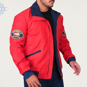 May include: Red Baywatch Lifeguard jacket with navy blue accents on the collar, cuffs, and pockets. Features a "Baywatch Lifeguard" patch on the left chest. The jacket has a zipper closure and a classic bomber jacket style.