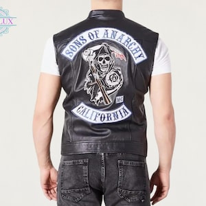 May include: Black leather vest with a Sons of Anarchy patch on the back. The patch features a skull with a scythe, the words "Sons of Anarchy" and "California". The vest is sleeveless and has a high collar.