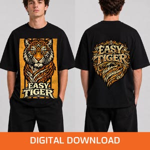 Puede incluir: Una camiseta negra de manga corta con un gráfico de una cabeza de tigre en la parte delantera dentro de un marco rectangular amarillo con el texto "EASY TIGER" debajo. La parte posterior de la camiseta muestra un emblema dorado estilizado con el texto "EASY TIGER".