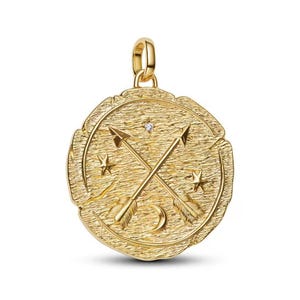 May include: Gold-colored pendant with a textured surface, featuring crossed arrows, stars, and a crescent moon design. A small diamond is set near the center. The pendant has a loop for a chain.