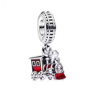 Puede incluir: Un charm de plata con un diseño de locomotora. La locomotora presenta detalles rojos en la parte delantera y en las ventanas, con ruedas y una chimenea plateadas. El charm está diseñado para ser adjuntado a una pulsera o collar.