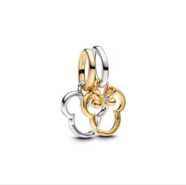 Puede incluir: Un charm dorado y plateado con un dise&ntilde;o de cabeza de Mickey Mouse. El charm dorado tiene una flor con un peque&ntilde;o diamante en el centro. El charm plateado tiene grabada la palabra "Better". El charm dorado tiene grabada la palabra "Together".