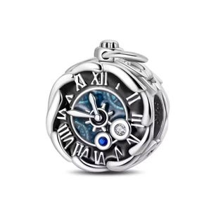 Könnte beinhalten: Ein silberfarbener Charm in Form einer Taschenuhr. Das Zifferblatt hat römische Ziffern und ein blau-silbernes Design. Zwei kleine Edelsteine sind in der Nähe der Mitte gesetzt. Der Charm hat oben eine Schlaufe.