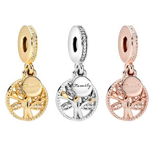 Könnte beinhalten: Drei Charm-Anhänger mit einem Lebensbaum-Design. Einer ist goldfarben, einer silberfarben und einer roségoldfarben. Jeder Charm hat einen runden Anhänger mit dem Wort "Family" und ist mit klaren Kristallen verziert.