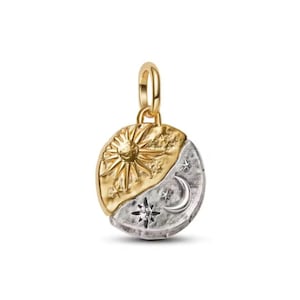 Può includere: Un ciondolo in oro e argento con un design celeste. La metà superiore presenta un sole dorato con raggi e stelle, mentre la metà inferiore ha una luna argentata, stelle e una gemma centrale. Il ciondolo ha un anello d'oro per una catena.